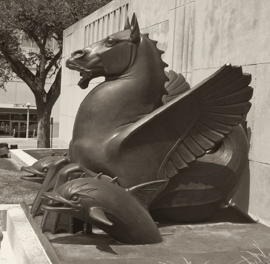 Warm-toned black and white print of the bronze hippocamp outside Kansas City's city hall, a winged sea horse rearing over three bronze fish.