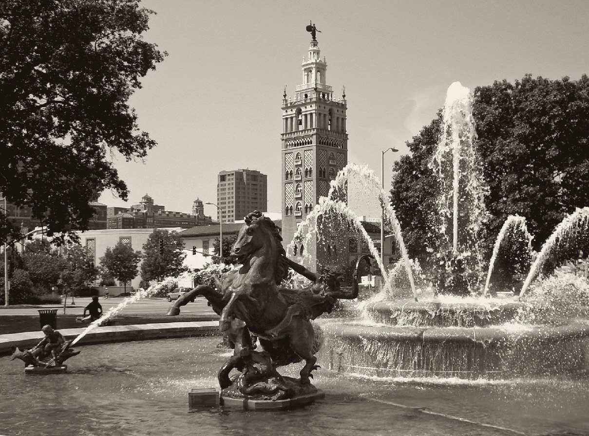 Warm-toned black and white print of the J.C. Nichols fountain, a rearing bronze horse in the spray with the Giralda tower standing behind it.