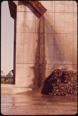 Waste water running down a stained concrete wall into the Kansas River.