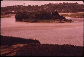 A low wooded island splitting the Kansas River, the water gone pink on expired film.
