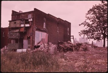 A brick two-story house left standing on a cleared block.