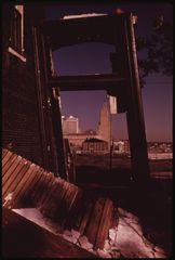 The gutted frame of a house, downtown visible through the missing wall.