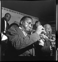 Four musicians crowded onto a small stage, two trumpets in front, the drummer behind.